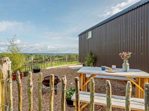 a backyard with a wooden table and a fence at 1 Bed in Hereford oc-93441 in Little Dewchurch
