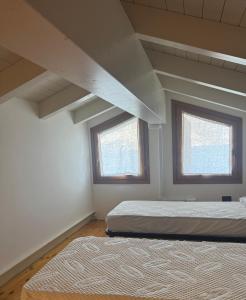 two beds in a room with two windows at BellaIseo Luxury rooftop in Pilzone