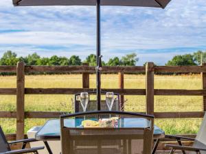 a table with glasses and an umbrella in front of a field at 3 Bed in Aylesbury oc-88963 in Shabbington +14 photos