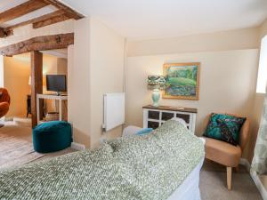a bedroom with a bed and a chair and a television at Quince Cottage in Lewes