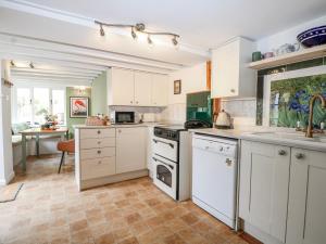 a kitchen with white cabinets and white appliances at Quince Cottage in Lewes