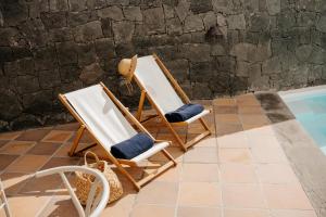 two beach chairs sitting next to a swimming pool at Villa Volcano by CasasBlancas in Yaiza