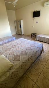 a large bed in a room with a flat screen tv at Império Hotel in Costa Rica