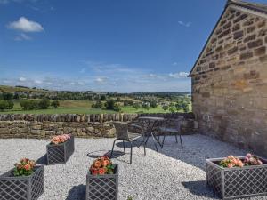a patio with a table and chairs and a stone wall at 1 Bed in Bakewell oc-91367 in Youlgreave