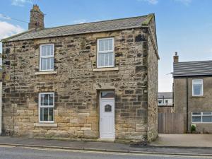 an old stone house with a white door on a street at 2 Bed in Morpeth oc-91206 in Amble