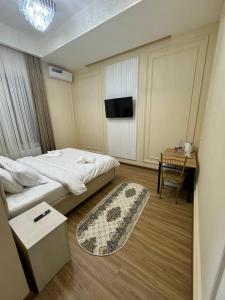 a bedroom with a bed and a table and a television at Old City Samarkand Hotel in Samarkand