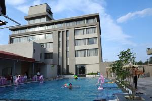 a group of children playing in a swimming pool in front of a building at Manratan Resort in Narsinghgarh