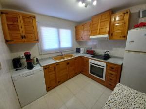 a small kitchen with wooden cabinets and a white refrigerator at Marcolina, 2 in Alcalà de Xivert