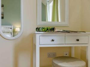 a white dressing table with a mirror and a stool at 1 Bed in Cinderford oc-88272 in Cinderford