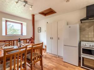a kitchen with a table and a white refrigerator at 2 Bed in High Peak oc-pk551 in Hayfield