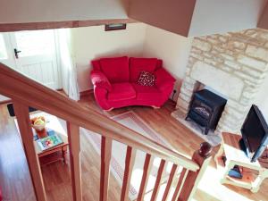a red chair in a living room with a fireplace at 2 Bed in Cirencester oc-cc094 in Ewen
