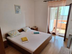 a bedroom with a large white bed with a window at Apartmani Štefica in Razvala