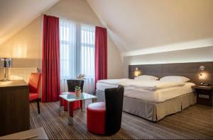 a hotel room with a large bed with red curtains at Béni golf club Clervaux hôtel & Restaurant in Eselborn