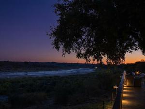 a view of a river at sunset with a tree at Buckler's Africa Lodge Kruger Park in Komatipoort