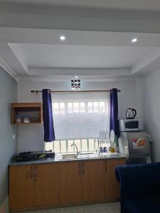 a kitchen with a sink and a window with blue curtains at Pivot Studio near Westside mall in Nakuru