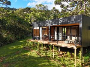 a black house on a wooden deck in a forest at Mökki Cabanas de Altitude INAUGURAÇÃO ABRIL 2026 in Urubici