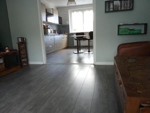 a living room with a wooden floor and a kitchen at Le lagon zen in Ploufragan