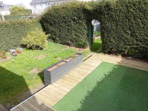 a garden with a wooden walkway and an archway at Le lagon zen in Ploufragan