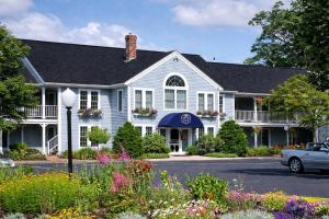 ein weißes Haus mit Blumen davor in der Unterkunft Cod Cove Inn, BW Signature Collection-Boothbay Harbor Area in Edgecomb