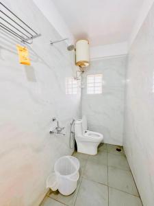 a white bathroom with a toilet and a sink at SHR Comfort Near Reva Circle Yelahanka in Bangalore