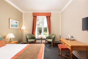 a hotel room with a bed and a desk and chairs at Coulsdon Manor Hotel and Golf Club in Croydon