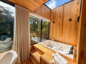 a bath tub in a room with a large window at Mökki Cabanas de Altitude INAUGURAÇÃO ABRIL 2026 in Urubici