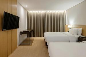 ein Hotelzimmer mit zwei Betten und einem Flachbildfernseher in der Unterkunft Anook Signature Hotel Incheon Guwol in Incheon