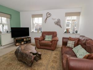 a living room with leather furniture and a flat screen tv at Awen Ingli in Newport