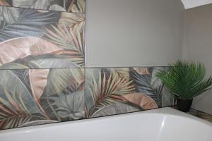 a bathroom with a tile wall with a plant at Blackburn Heights Sleeps 4 Family Apartment in Bridlington
