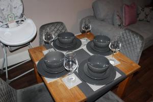 a table with plates and wine glasses on it at Blackburn Heights Sleeps 4 Family Apartment in Bridlington +11 photos