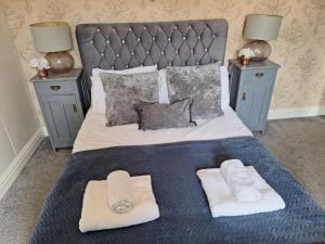 a bed with two pillows and towels on it at The Hampton Beautiful 3 Bedroom House with Conservatory & Garden in Scarborough