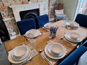 a wooden table with plates and wine glasses on it at The Hampton Beautiful 3 Bedroom House with Conservatory & Garden in Scarborough