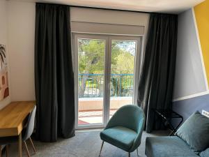 a living room with a window and a green chair at Hotel Elu Iris in Split