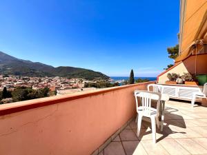 a balcony with two chairs and a view of a city at Le 3 case di Mia in Marciana Marina