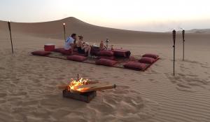 a group of people sitting around a fire in the desert at Hostel Desert Camp Sam in Jaisalmer +26 photos