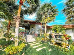 a house with palm trees in front of it at Social Escape Hotel Lemon Chalet in Ban Song Phi Nong