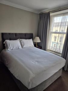 ein Schlafzimmer mit einem großen weißen Bett und einem Fenster in der Unterkunft Imperial Accommodation Tralee in Tralee