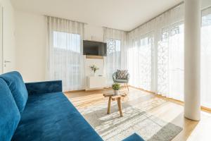 a blue couch in a living room with large windows at V7 Boutique Appartements in Freiburg im Breisgau +27 photos
