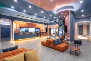 a living room with orange couches and a flat screen tv at Hanting Hotel Guangzhou Tianhe in Guangzhou
