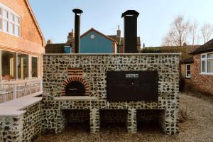 a stone fireplace in front of a house at Finest Retreats - ARC Next-The-Sea in Wells next the Sea