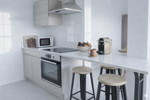 a white kitchen with a counter and stools in it at Verdant Comfort Apartment in Moka