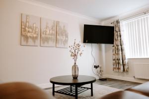 a living room with a table and a tv on the wall at Buckthorn Grove - 4 bed stunning home in Middlesbrough