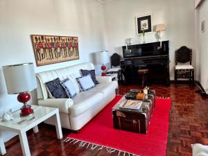 a living room with a white couch and a piano at Caparica for Rent in Costa da Caparica