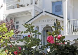 a white house with a white balcony and pink roses at Villa Hansa am Meer in Timmendorfer Strand