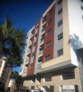 a tall building with a palm tree in front of it at Moroccan Inspired 2BR Bright, Central & New in Oulad Akkou