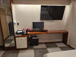 a desk with a computer and a television on a wall at a 모텔 in Seoul