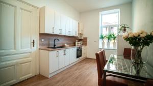 a kitchen with white cabinets and a glass table at Peony Apartment in Kroměříž