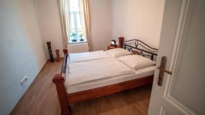 a bedroom with a bed with white sheets and a window at Peony Apartment in Kroměříž