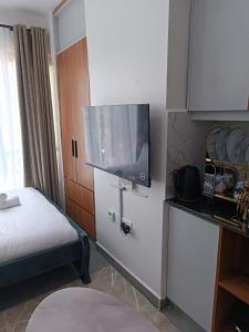 a small room with a bed and a flat screen tv at Cozy Studio Kiambu Town in Kiambu