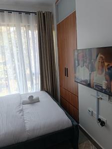 a bedroom with a bed and a flat screen tv at Cozy Studio Kiambu Town in Kiambu